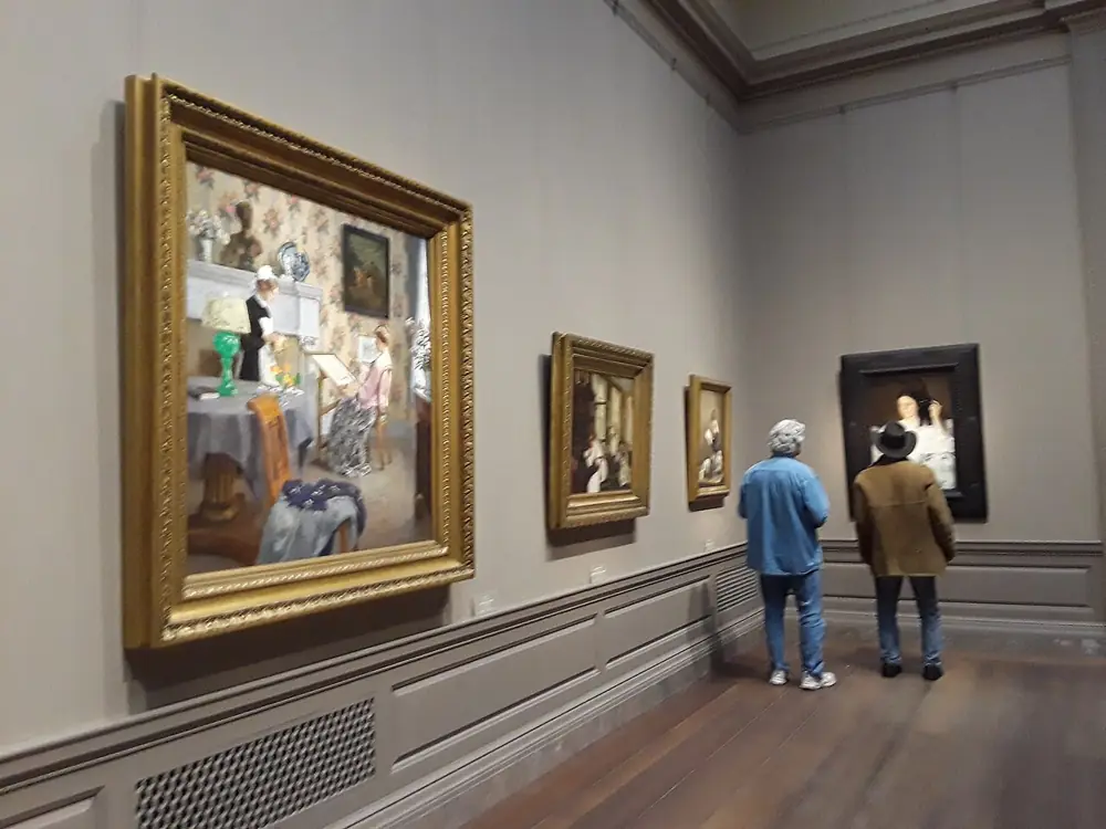 Visitors looking at paintings in a gallery